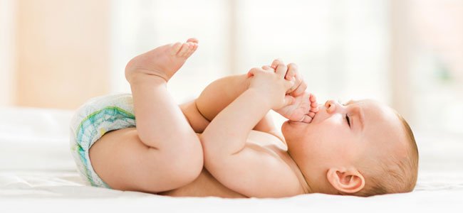 La imagen muestra un bebé explorando su cuerpo a través de los pies